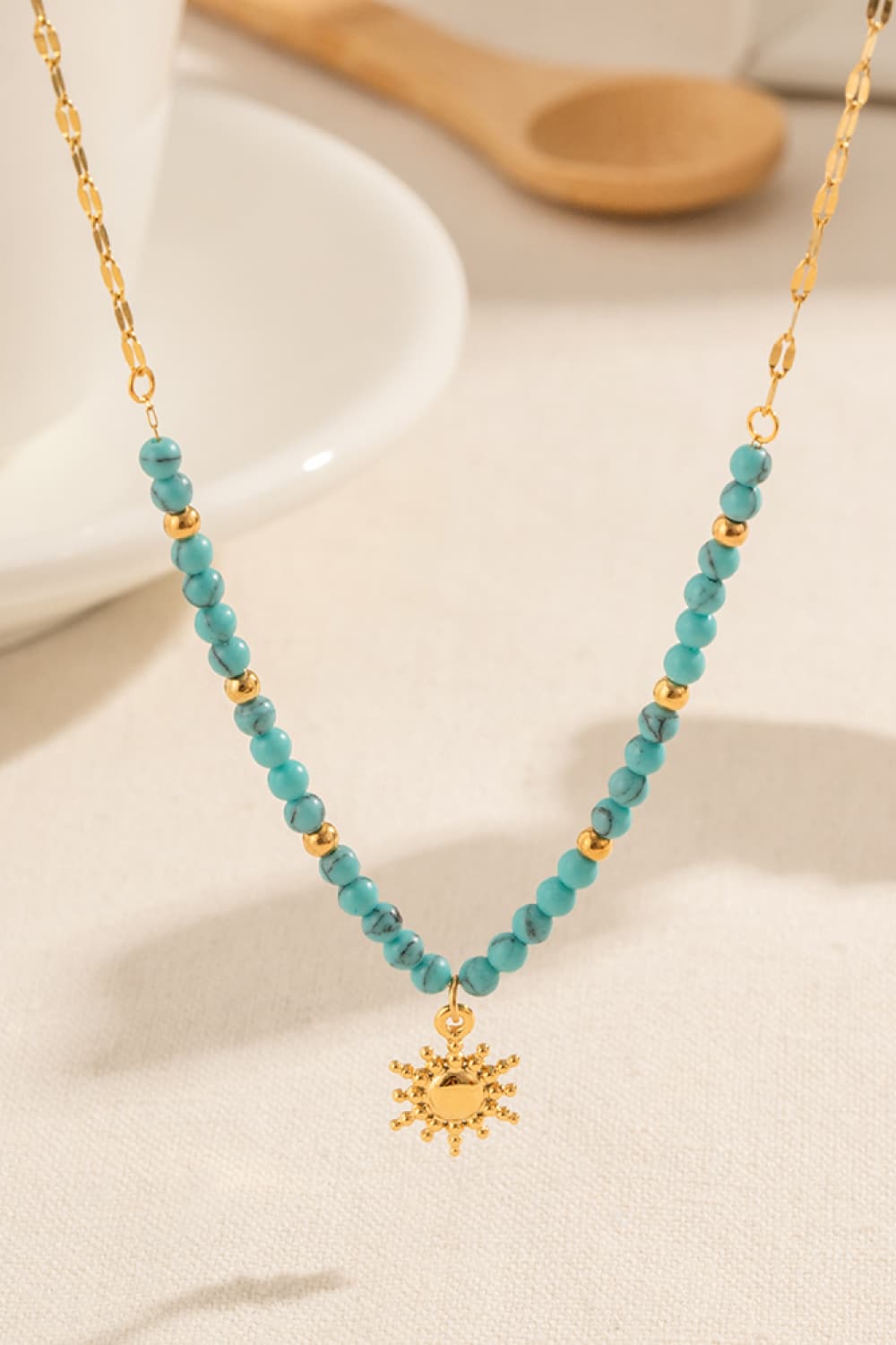 Turquoise beaded gold link necklace with small sun pendant charm in the center