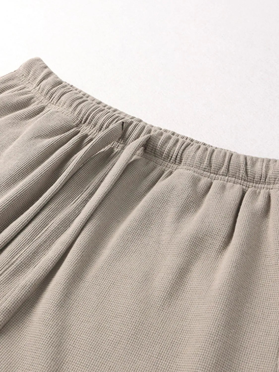 Elastic waistband and waffle texture on beige drawstring shorts with loose tie strings.