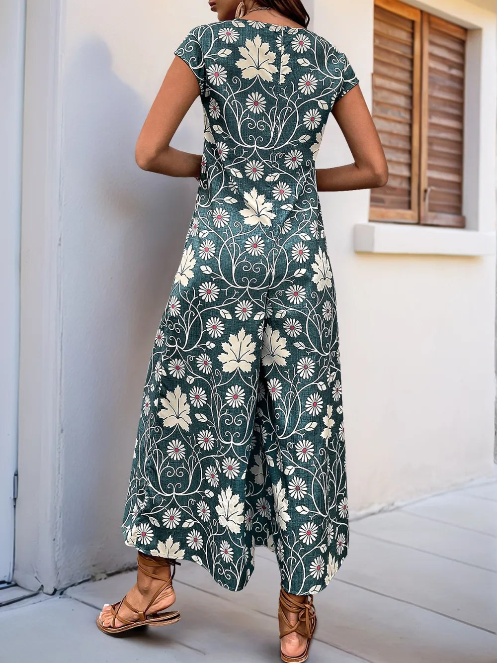 Back view of dark teal printed wide-leg jumpsuit with cap sleeves and wide legs