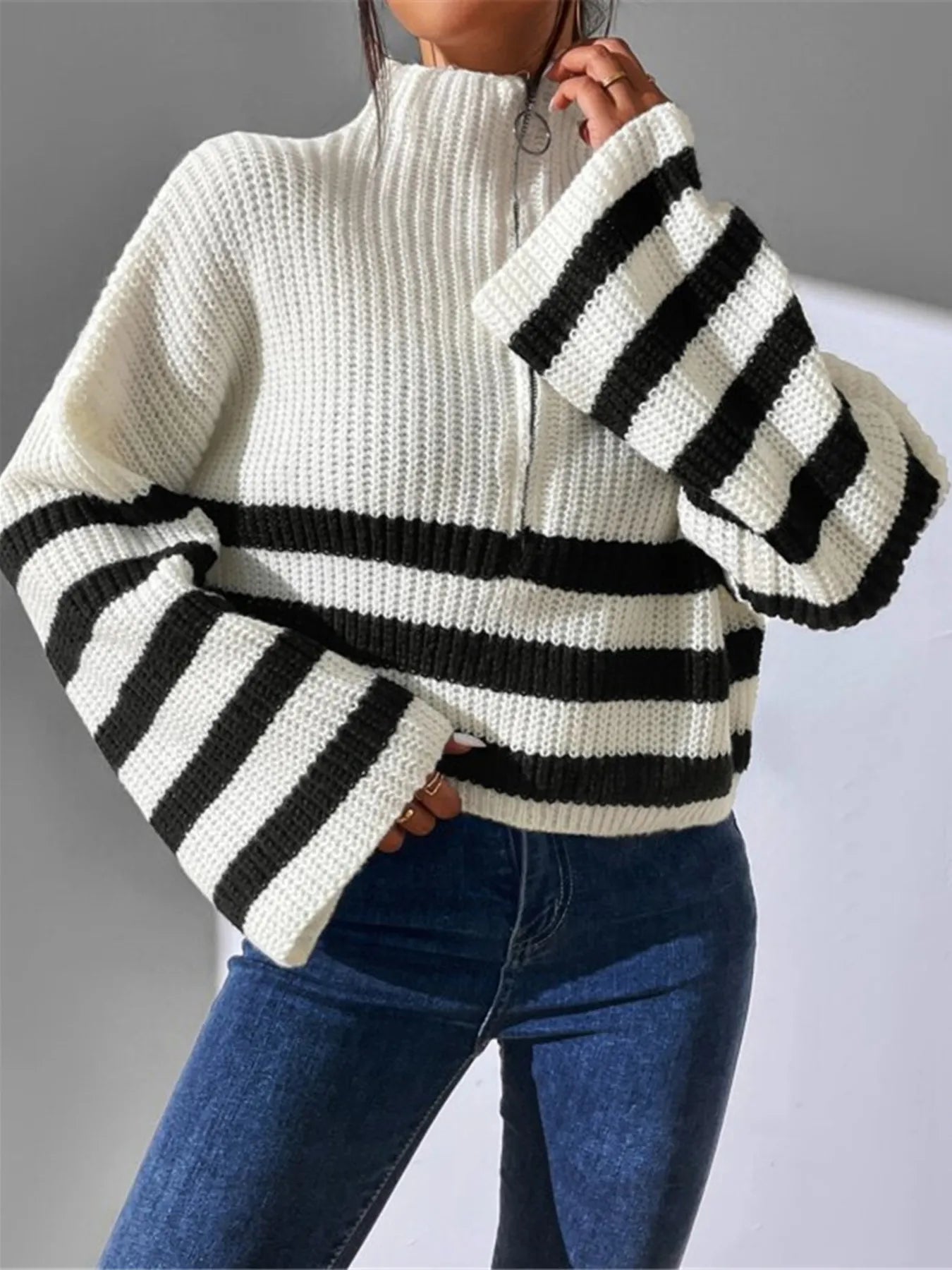 White cropped half-zip sweater with ribbed texture and bold black striped bands on sleeves