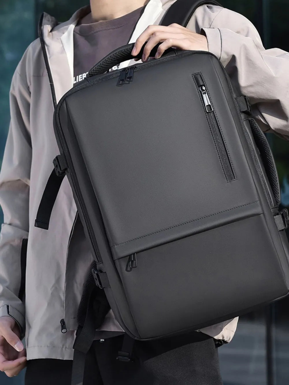 Dark gray backpack worn on shoulder, with front vertical zip pocket and padded back.