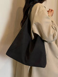 Black slouchy suede shoulder bag with open top and wide shoulder strap
