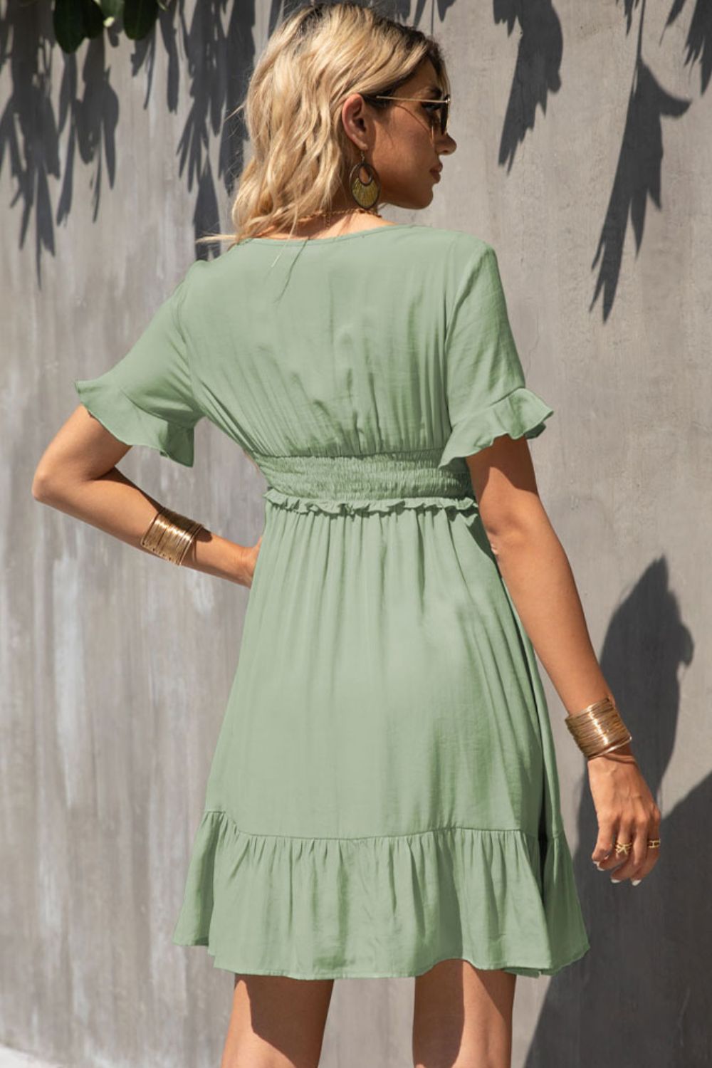 Light green smocked-waist V-neck back dress with tiered ruffle hem and flutter sleeves.