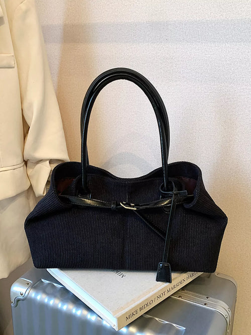 Black shoulder bag with curved handles, buckle closure, and hanging tag