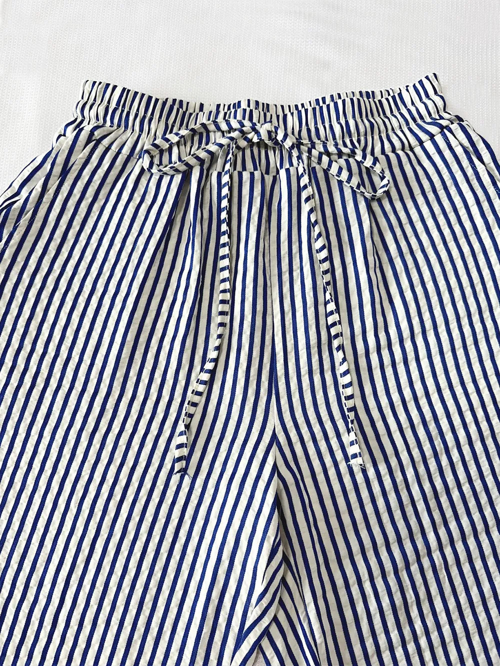 Striped elastic waist drawstring pants in blue and white, close-up of waistband tie