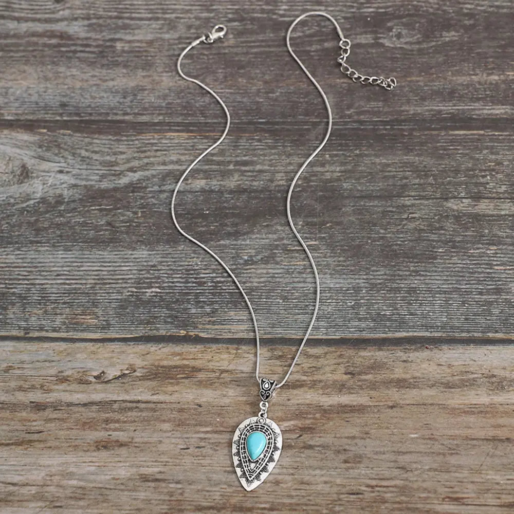 Silver pendant necklace with small teardrop charm and turquoise blue center stone