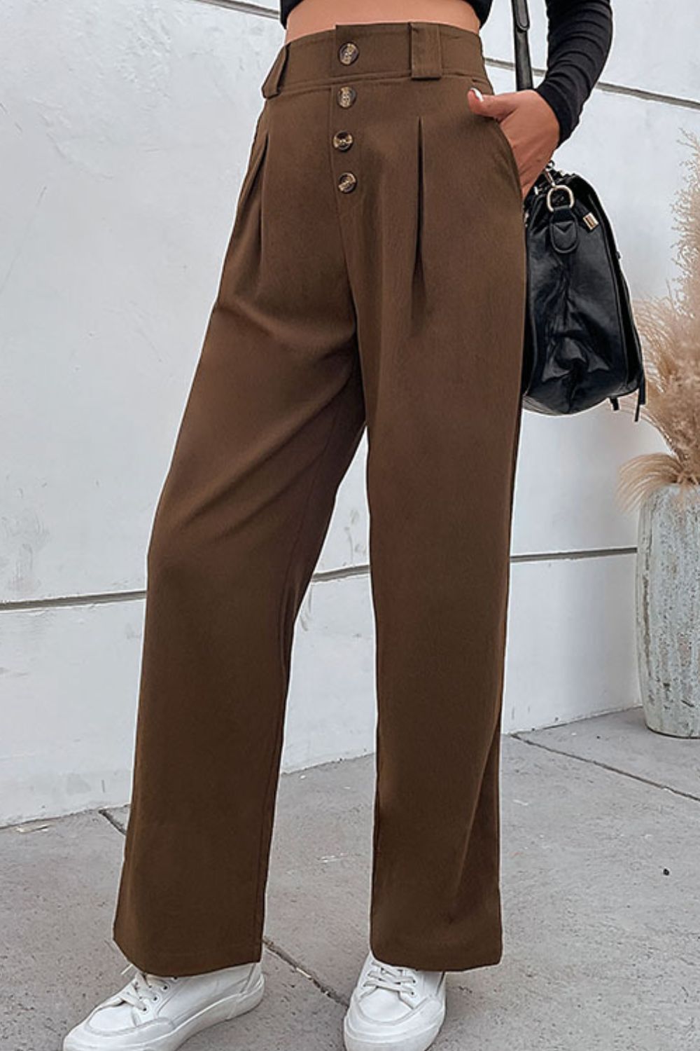 Brown wide-leg trousers with pleats, button fly, and front pockets at waist
