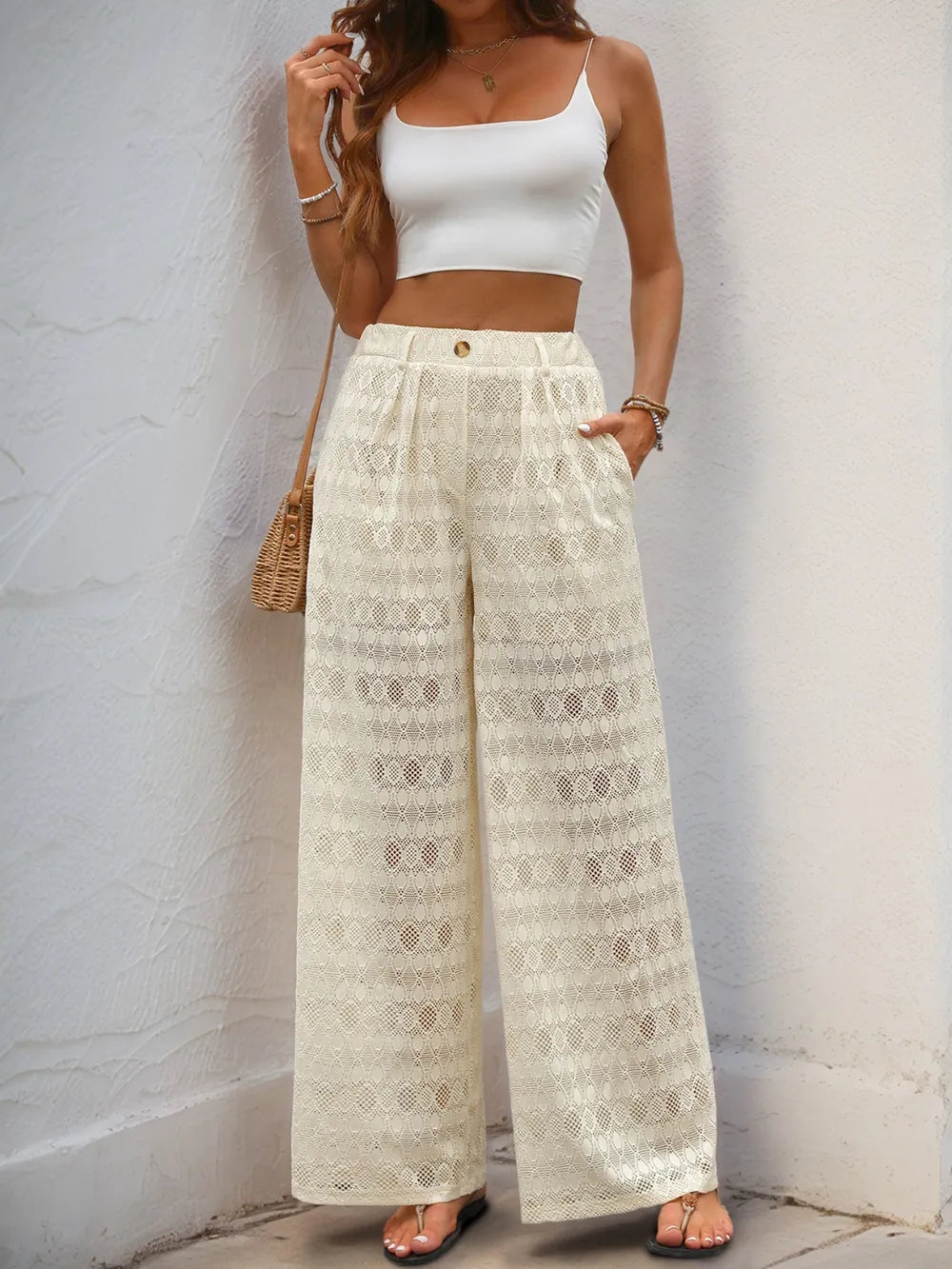 Cream wide-leg lace pants with decorative button waistband and full-length geometric lace texture