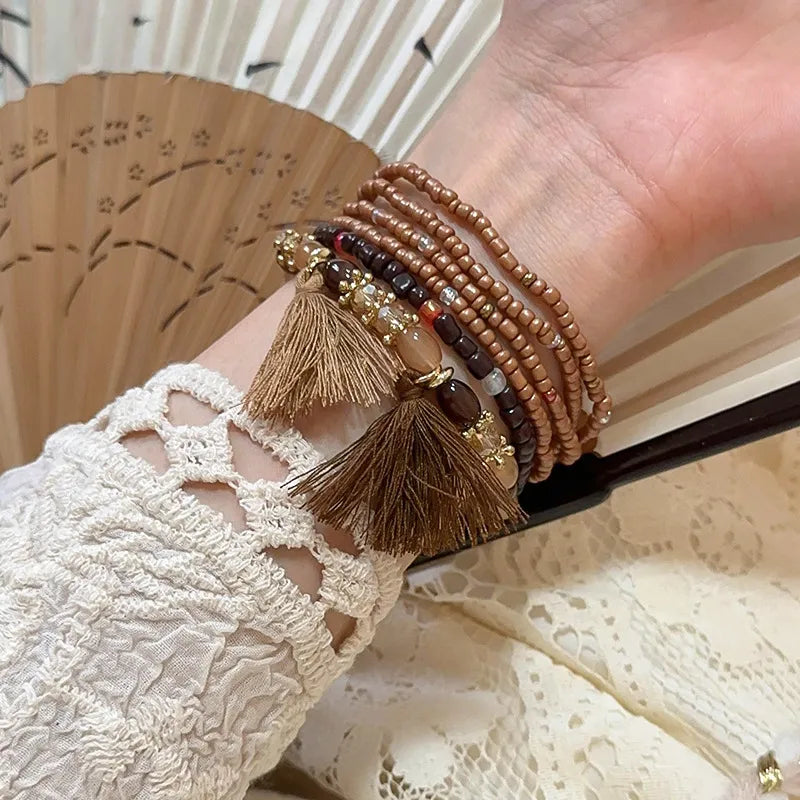Multi-strand bead tassel bracelet in brown tones with gold charms and small tassels