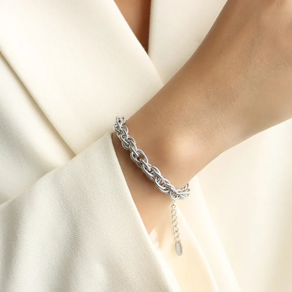 Silver chain bracelet with interwoven links and small dangling charm