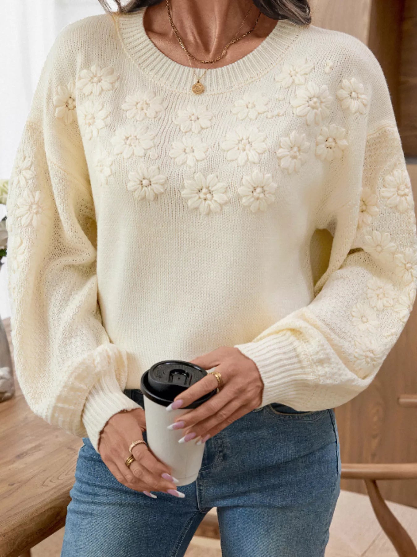 Cream floral knit sweater with round neck and long sleeves, ribbed cuffs and hem