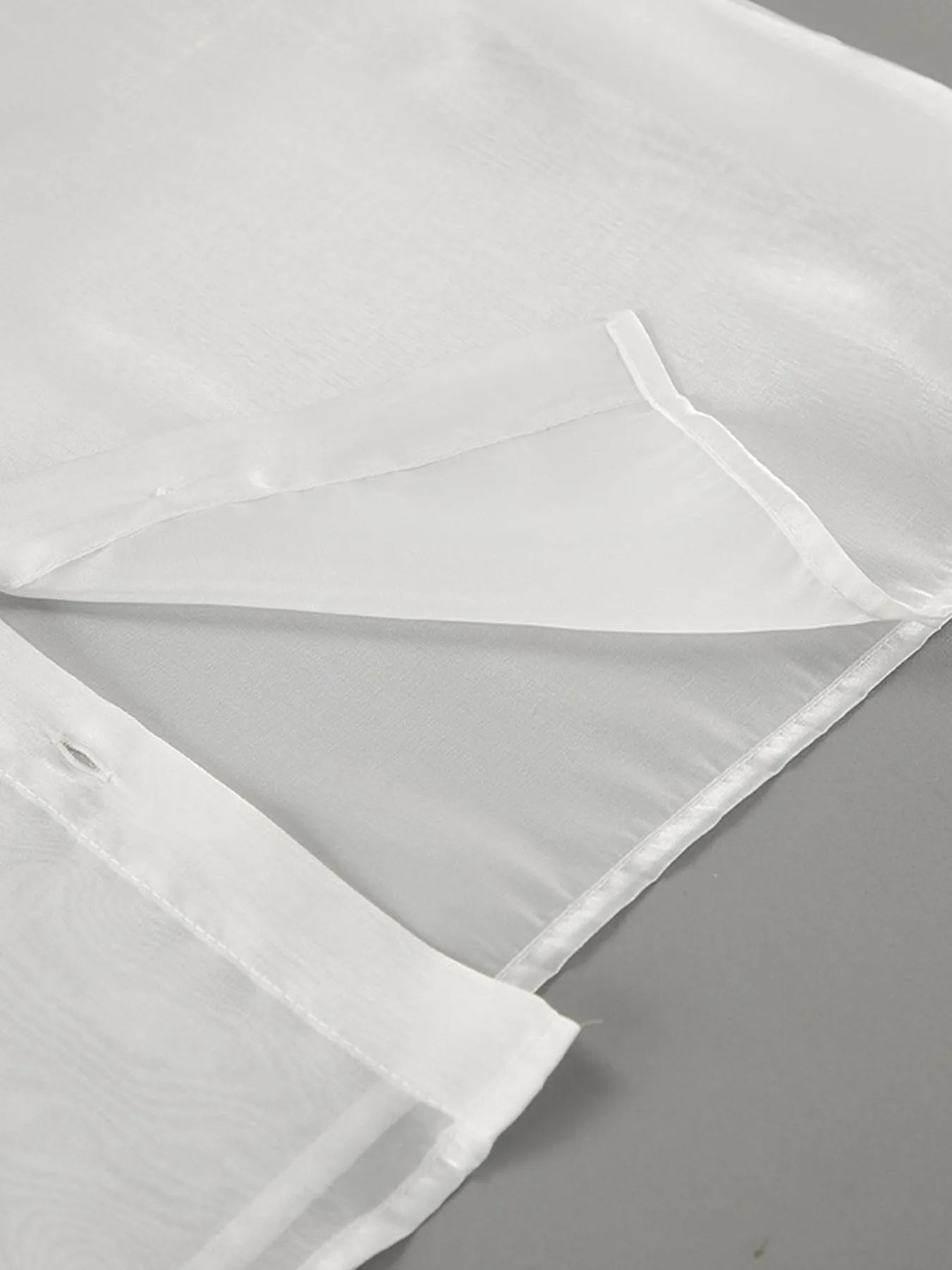 White button-up flounce sleeve shirt fabric and hem seam close-up