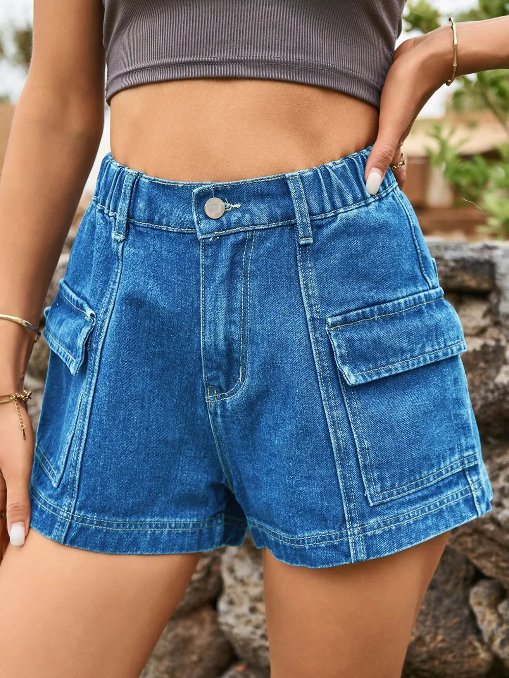 High-waist medium blue denim shorts with front button, belt loops, and cargo pockets