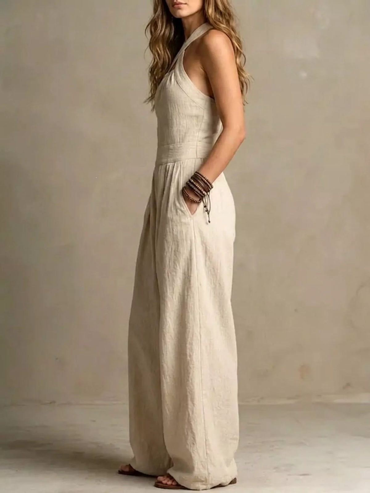 Off-white linen halter wide-leg jumpsuit in a side view with high waist pleats