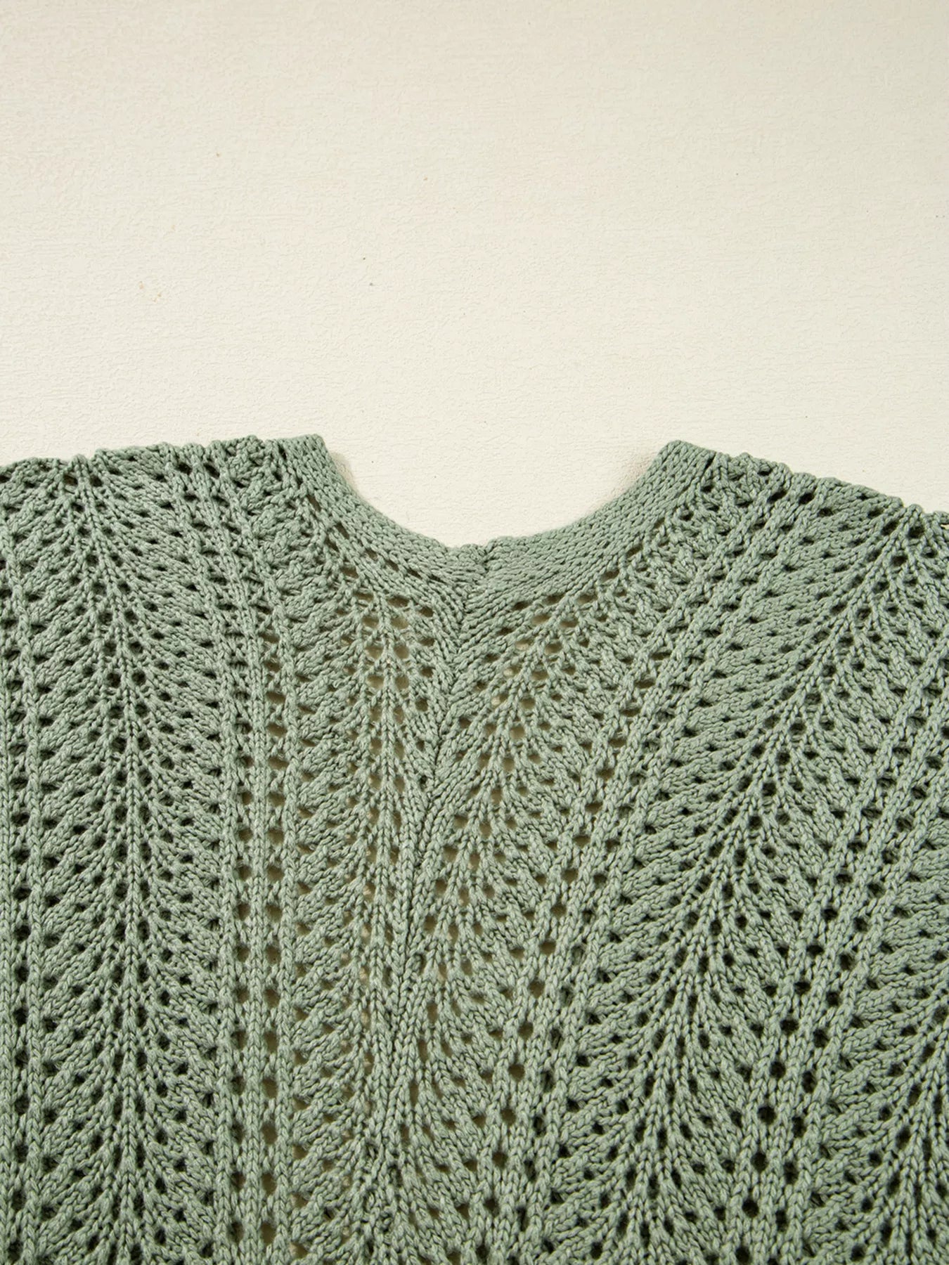 Sage eyelet knit cardigan with V-neckline and scalloped seam detailing, close-up.