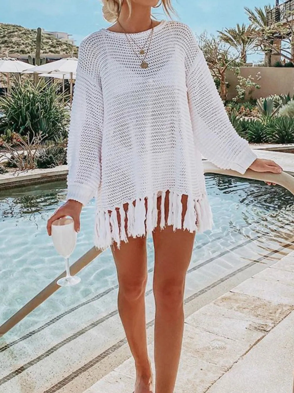 White long-sleeve openwork knit cover up with tassel fringe hem.