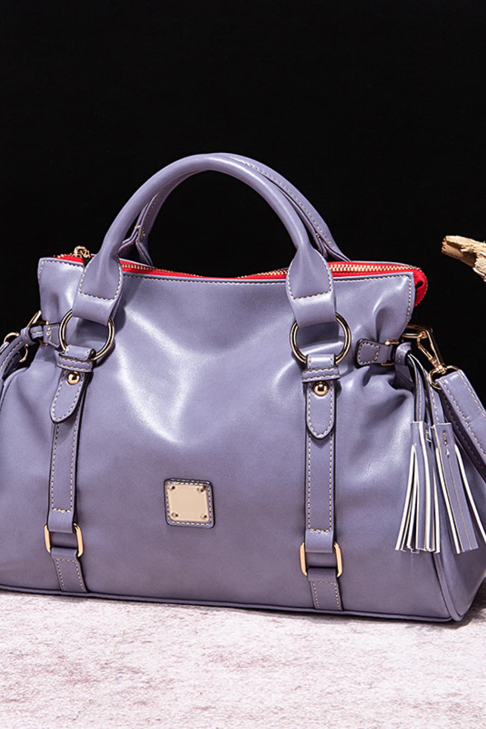 PU leather handbag in lavender with tassels, top handles, and front square patch.