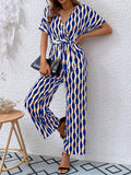 Blue-and-yellow printed surplice jumpsuit with tie waist, short sleeves, wide legs.