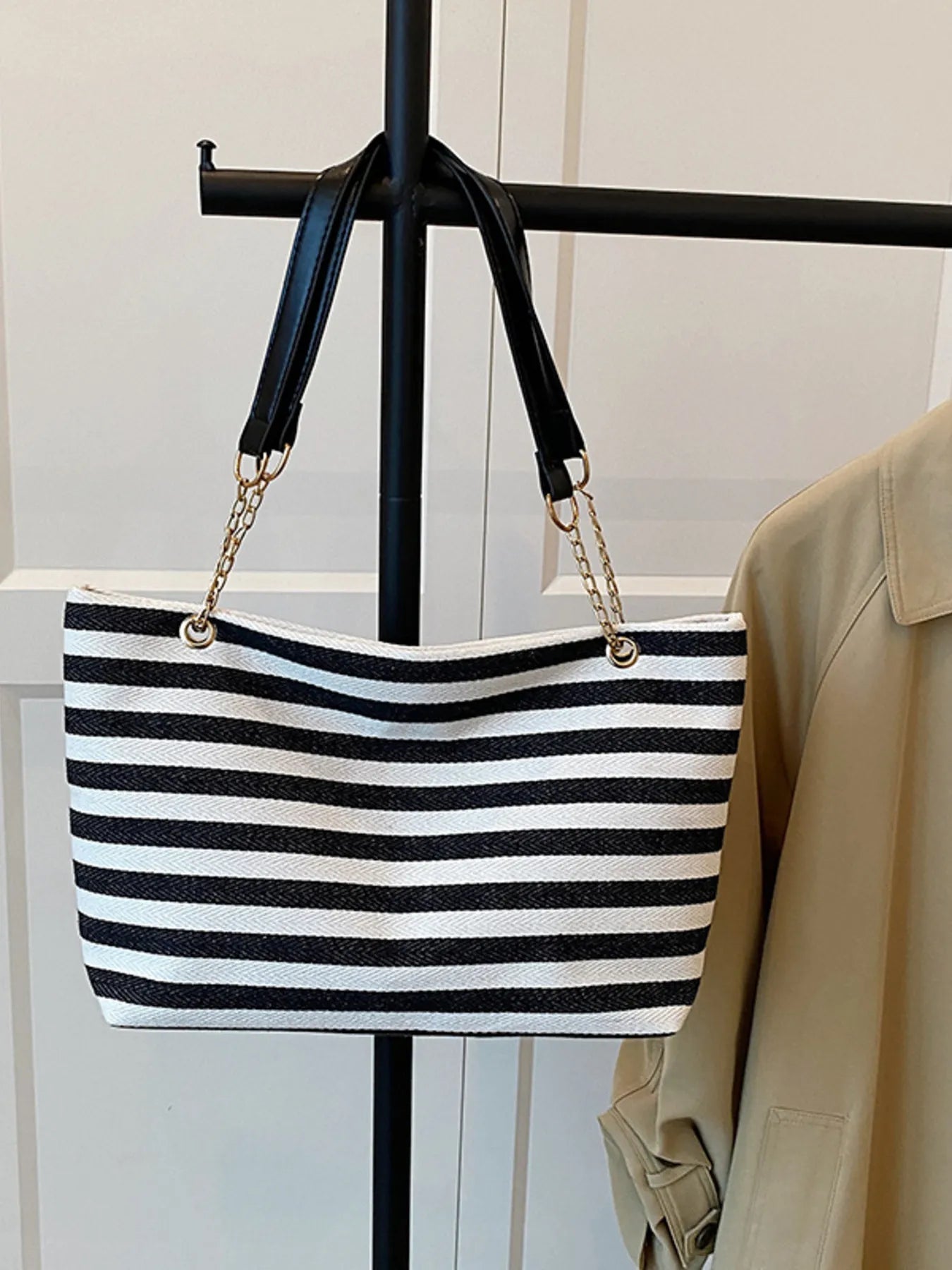 Black and white striped tote-style shoulder bag with gold chain straps and black side accents.