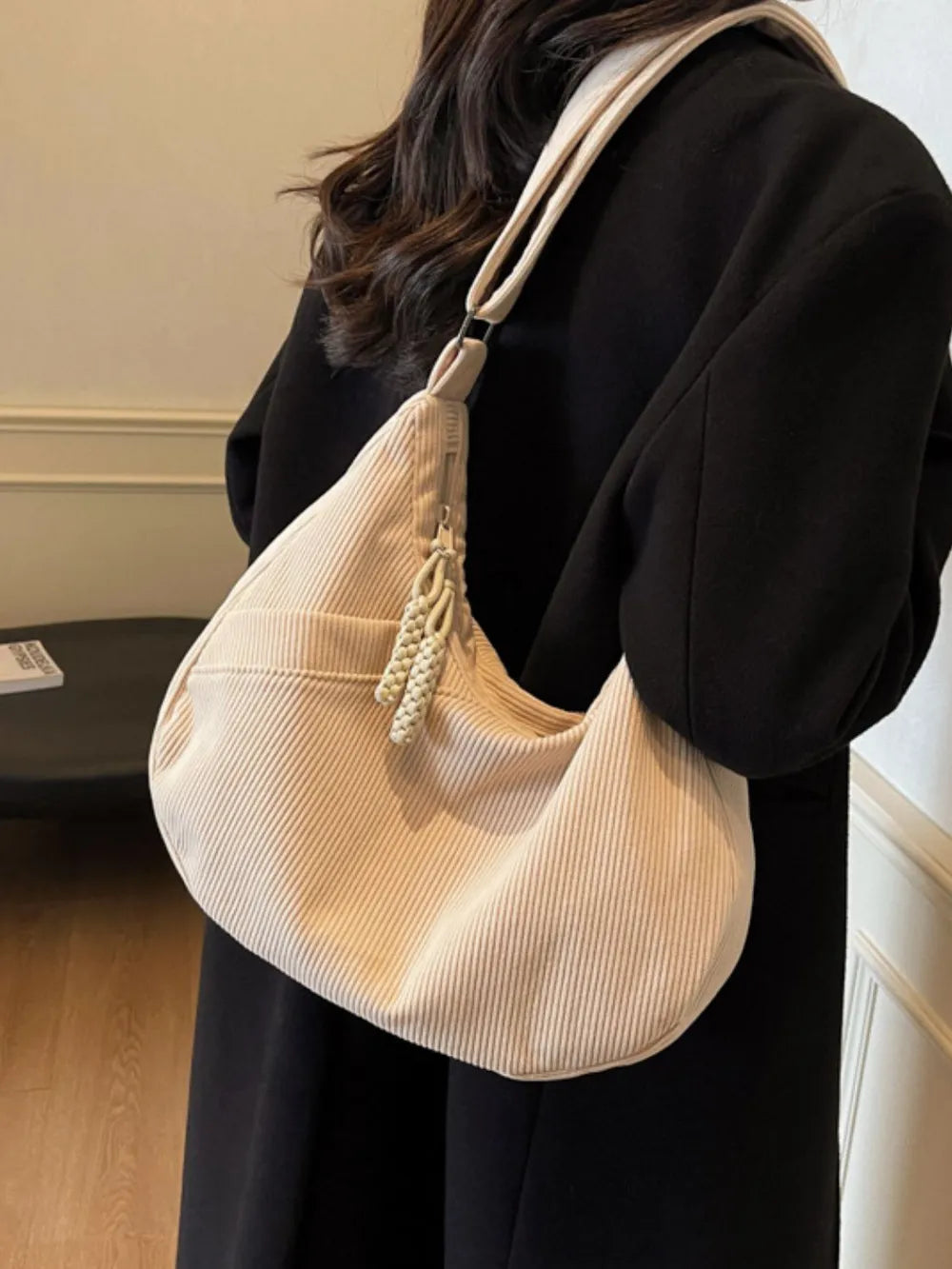 Beige ribbed hobo shoulder bag with adjustable strap and braided tassel charm