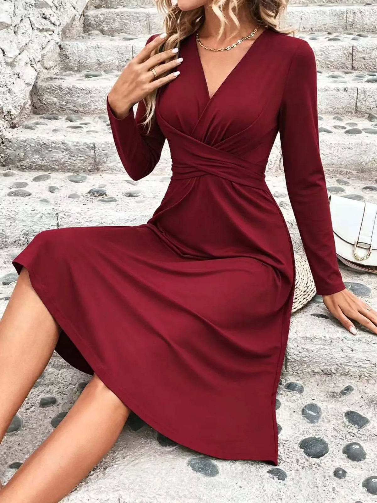 Burgundy long-sleeve midi dress with ruched crossover bodice and draped skirt.