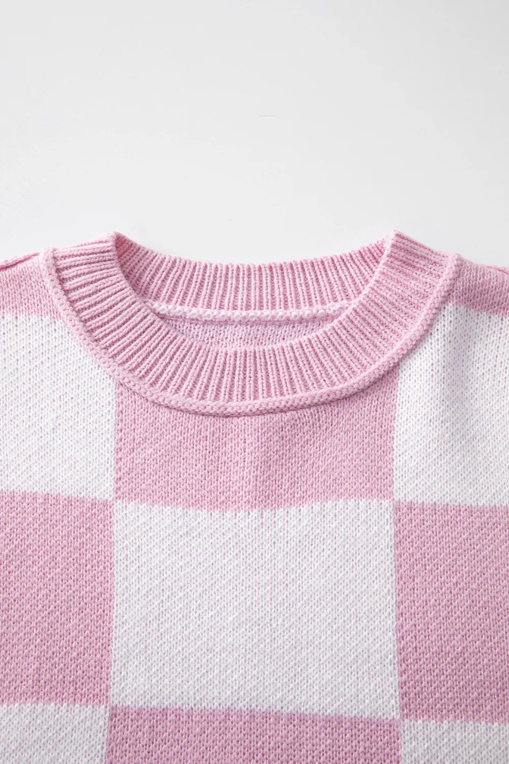 Pink and white checkered knit sweater with ribbed crew neck collar.