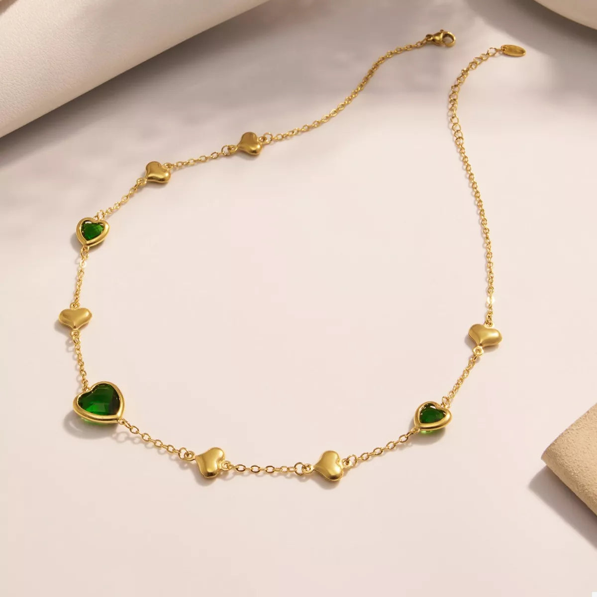 Gold-plated heart necklace with green glass heart charms and small heart links