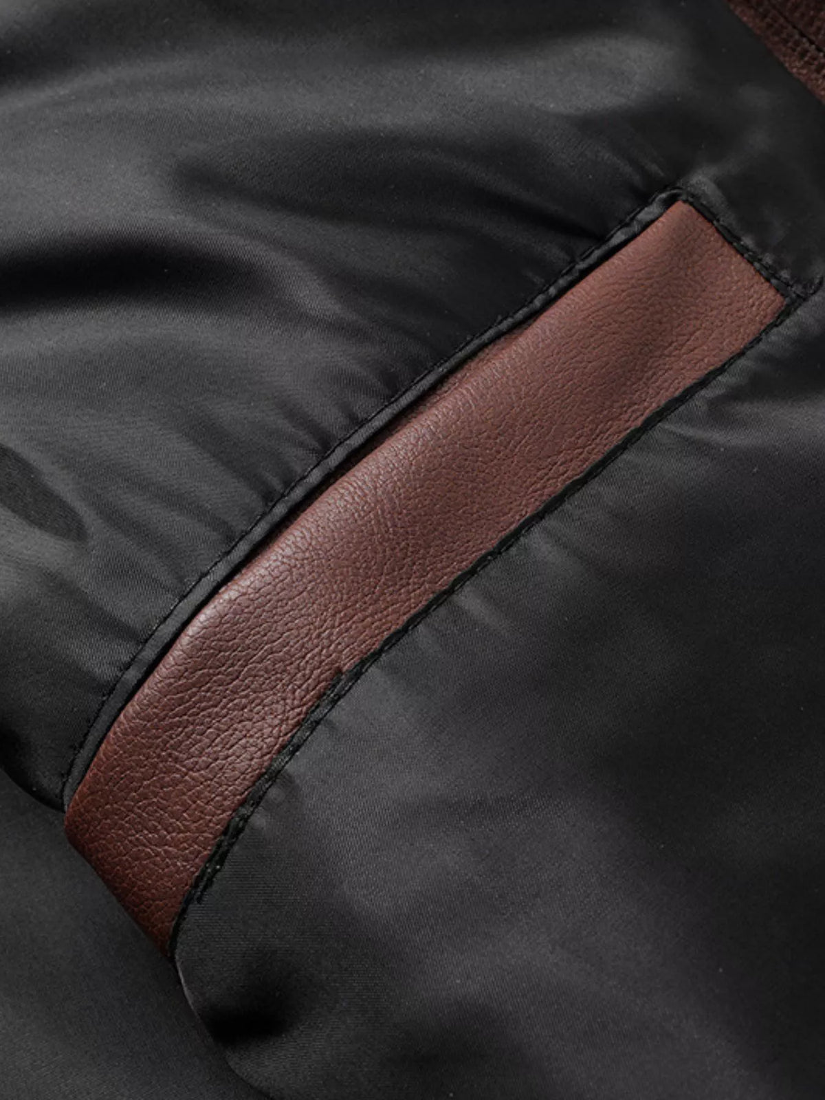 Close-up of vegan leather jacket seam with brown trim detail