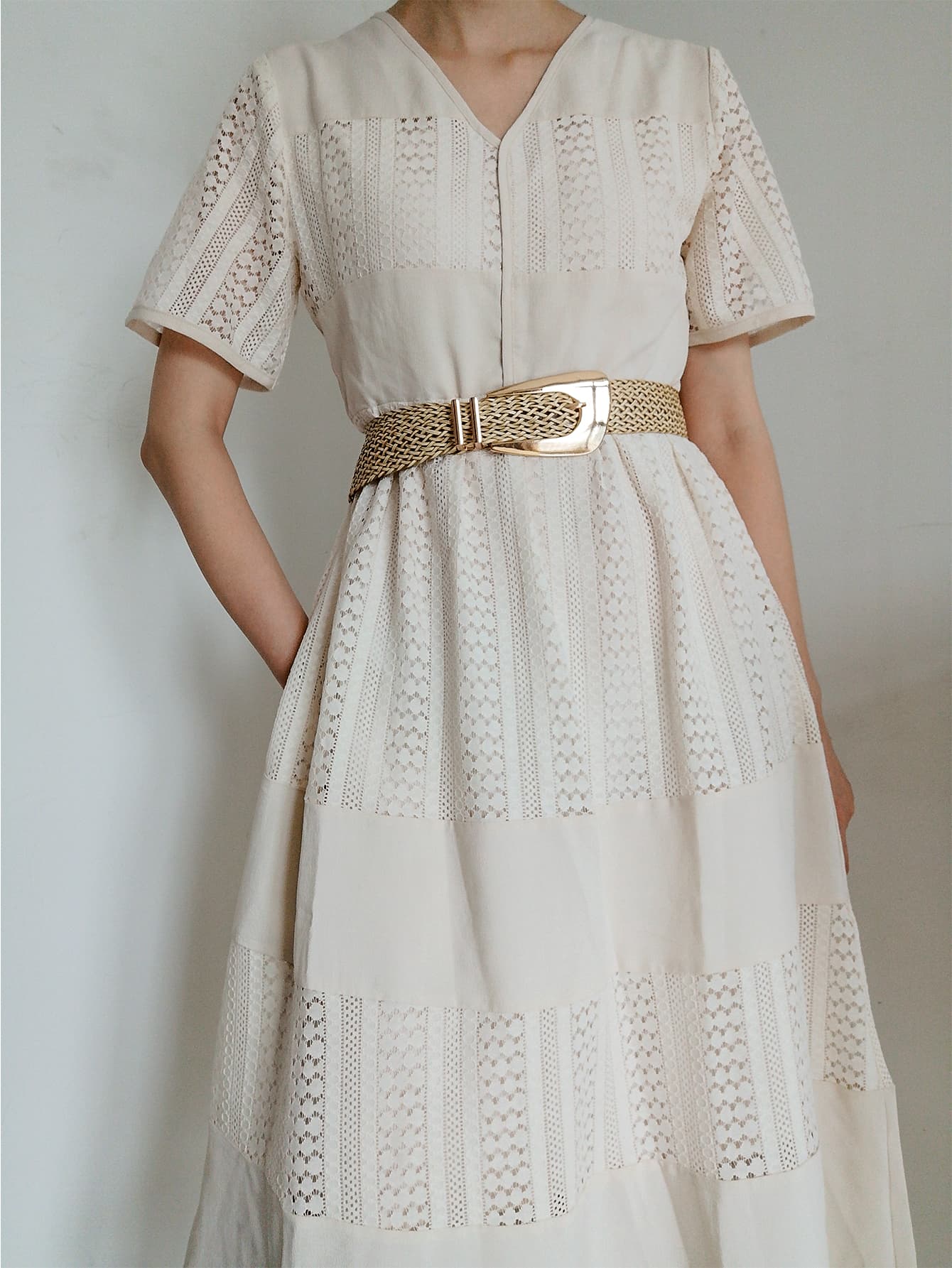 Woven braid belt with gold-tone irregular buckle around the waist of a dress