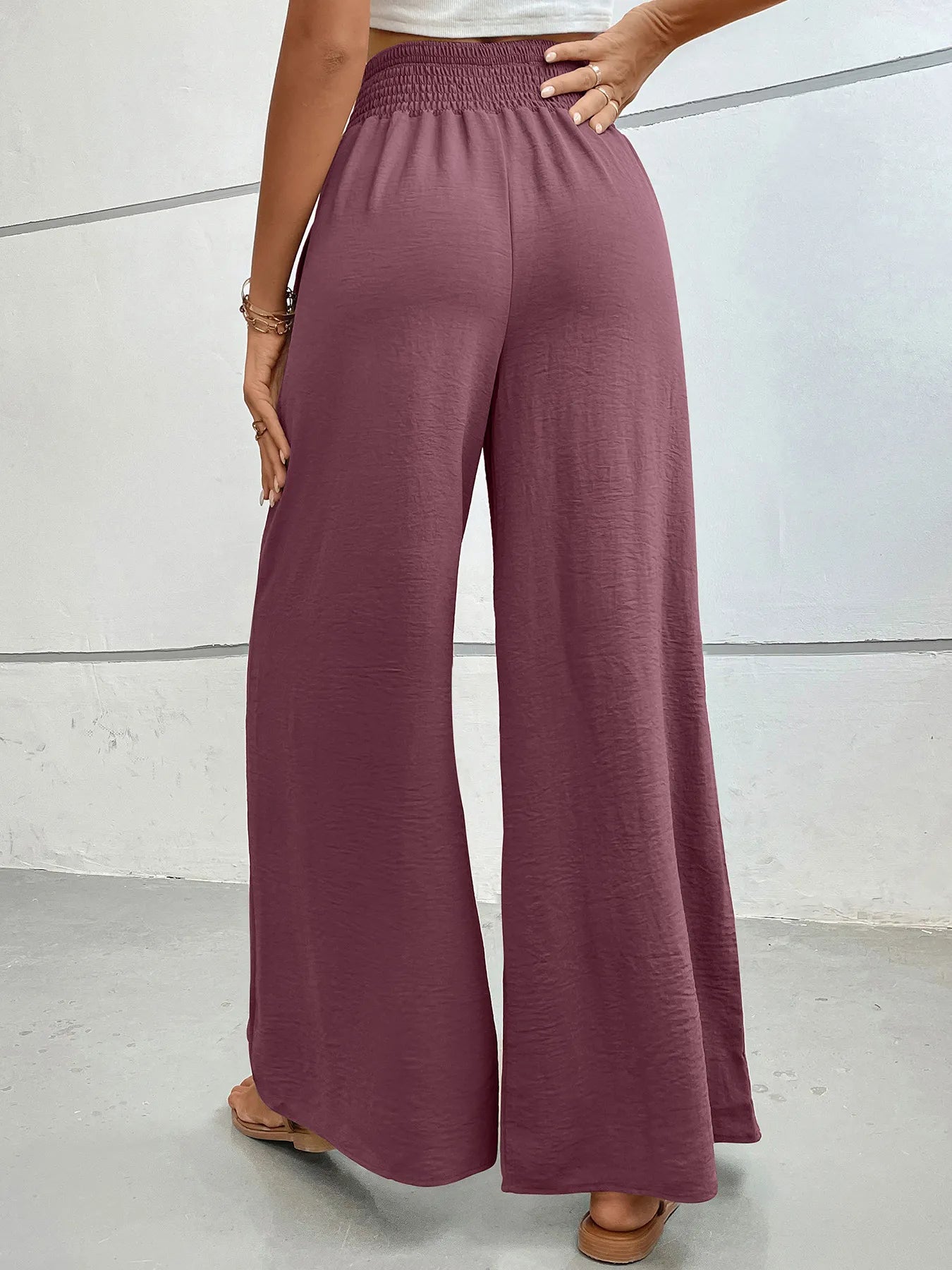 High-waisted wide-leg pants in mauve with elastic smocked waist and relaxed wide-leg drape.