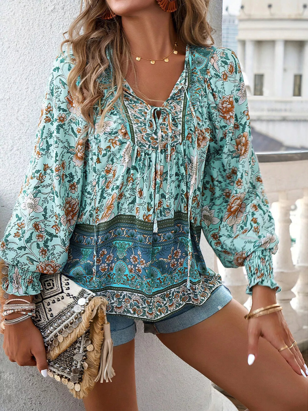 Teal floral tie-neck blouse with ruffled neckline, peplum hem, and elastic smocked cuffs