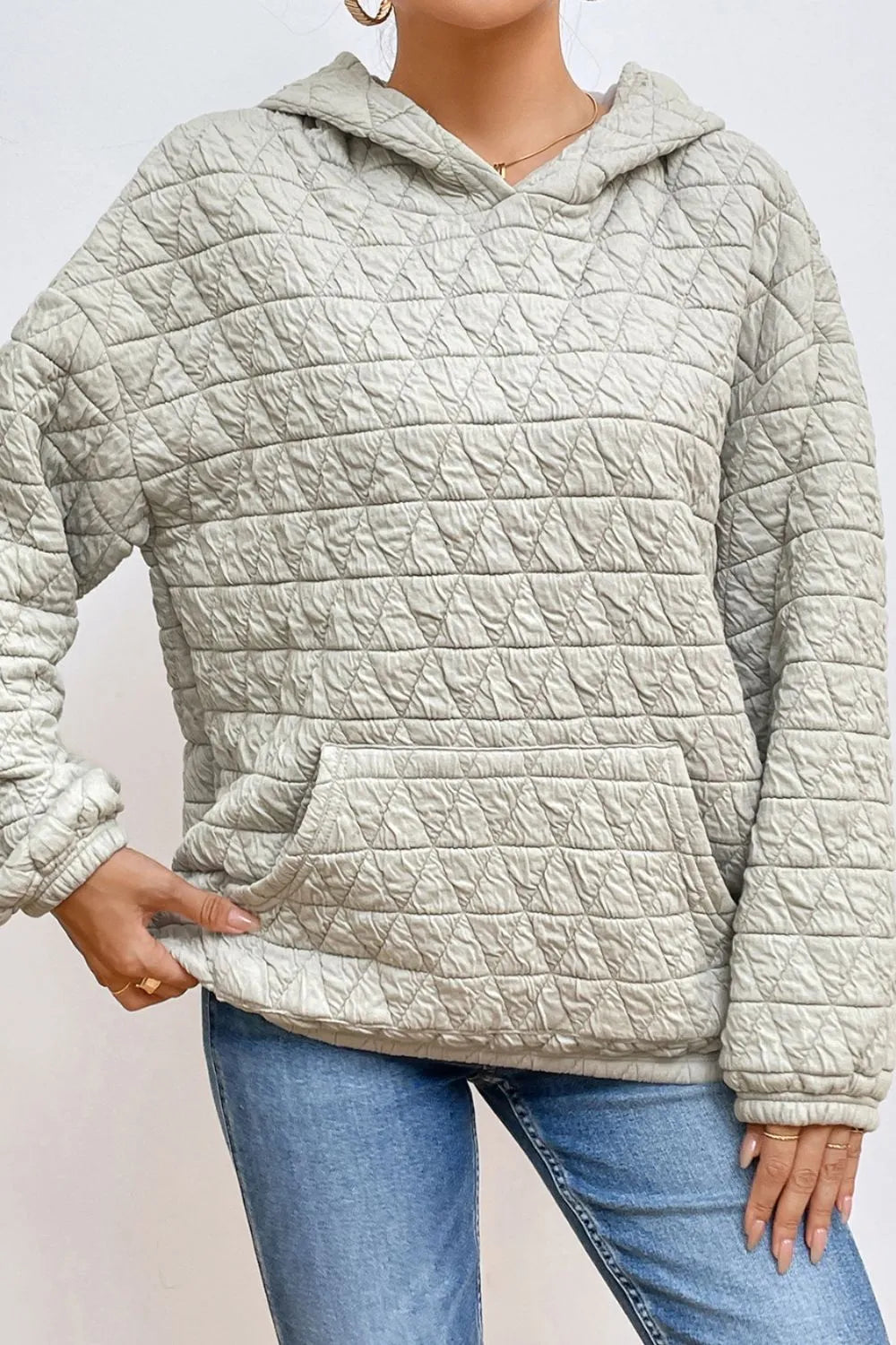 Light gray quilted long-sleeve hoodie with hood and front pocket, side view