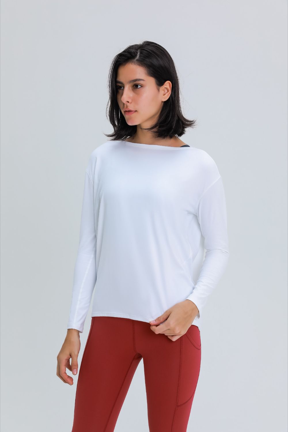Loose fit active top in white, front view with slightly curved hem and long sleeves.