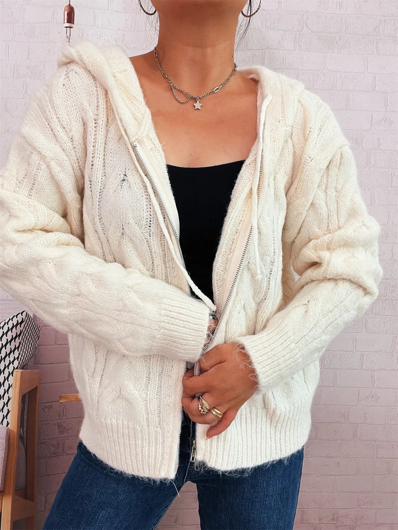 Cream hooded cable knit zip-up cardigan with front zipper, long sleeves and ribbed edges.