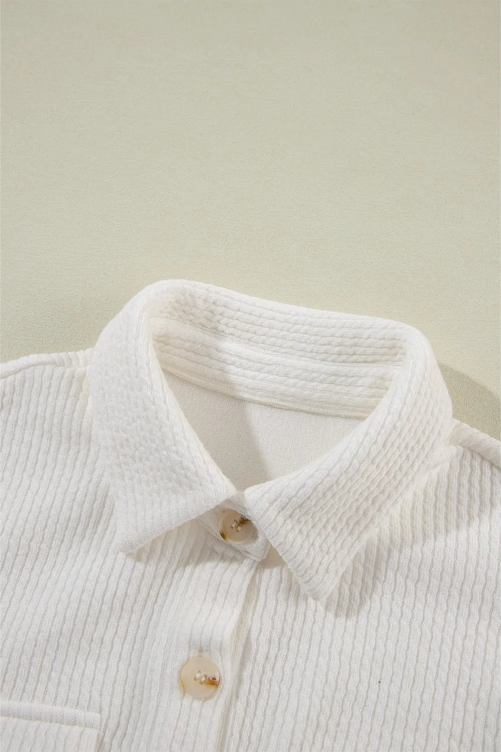 White shacket collar detail with button at neckline and ribbed texture.