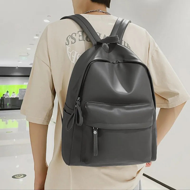 Dark gray vegan leather zip backpack worn on back with adjustable shoulder straps