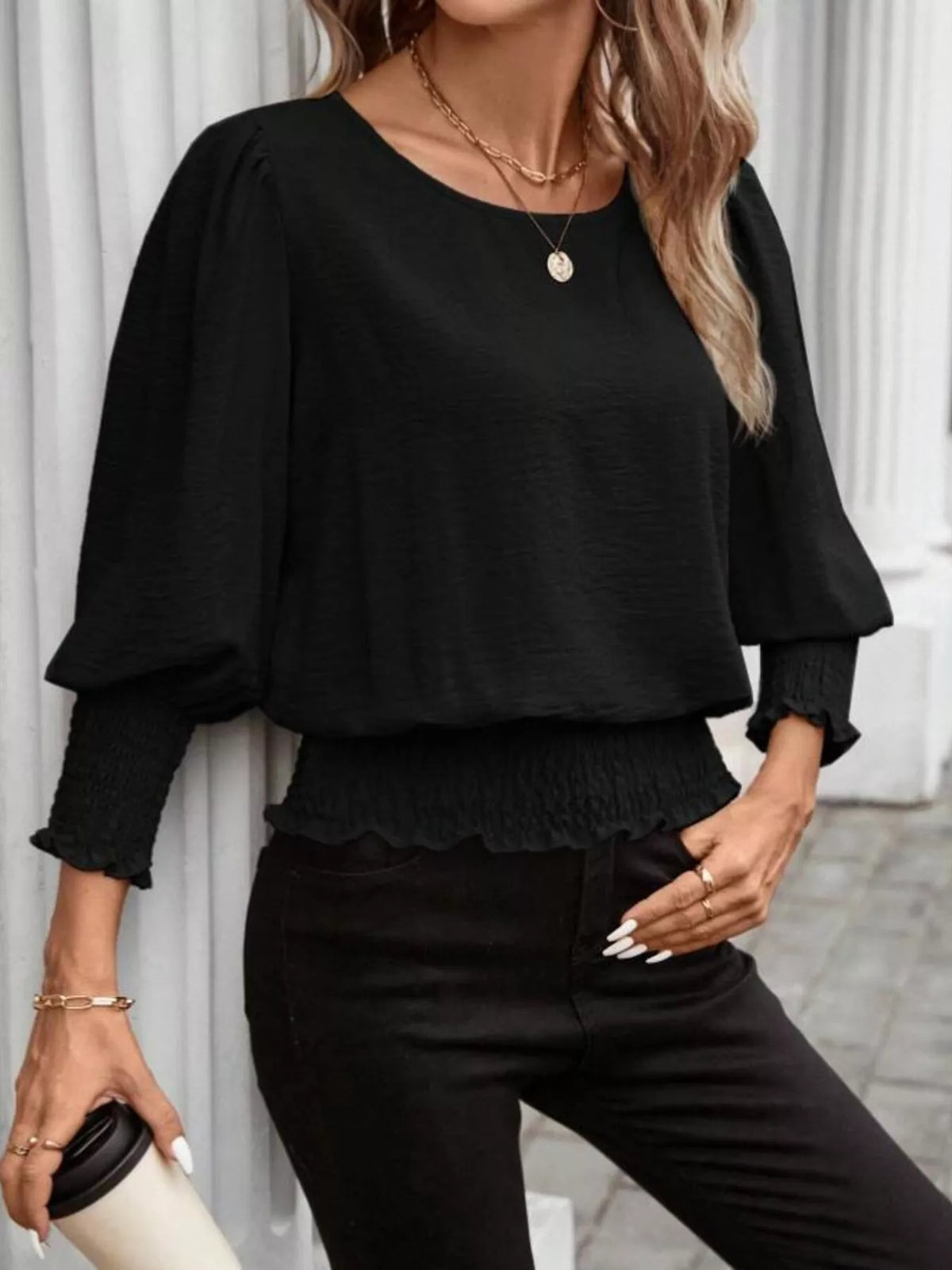 Black puff-sleeve smocked blouse with round neck, elastic cuffs, and gathered hem