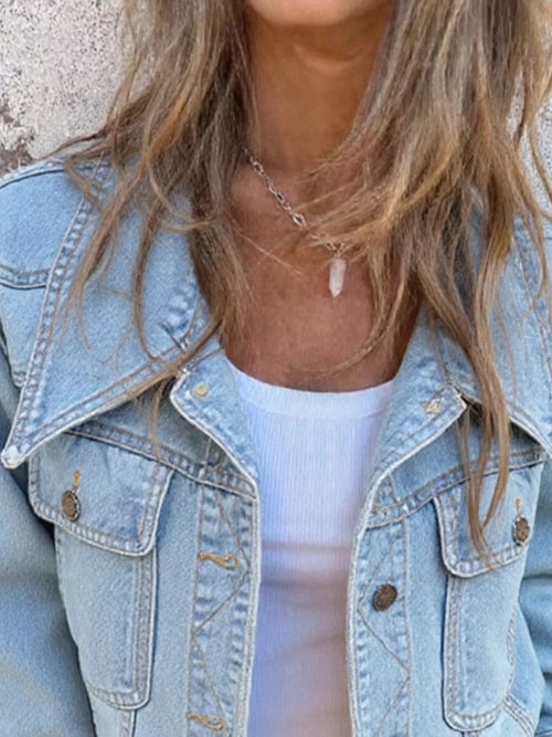 Light blue denim button-up jacket close-up: flap chest pockets and front buttons
