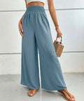 High-waisted wide-leg pants in dusty blue with smocked elastic waistband and flowing legs