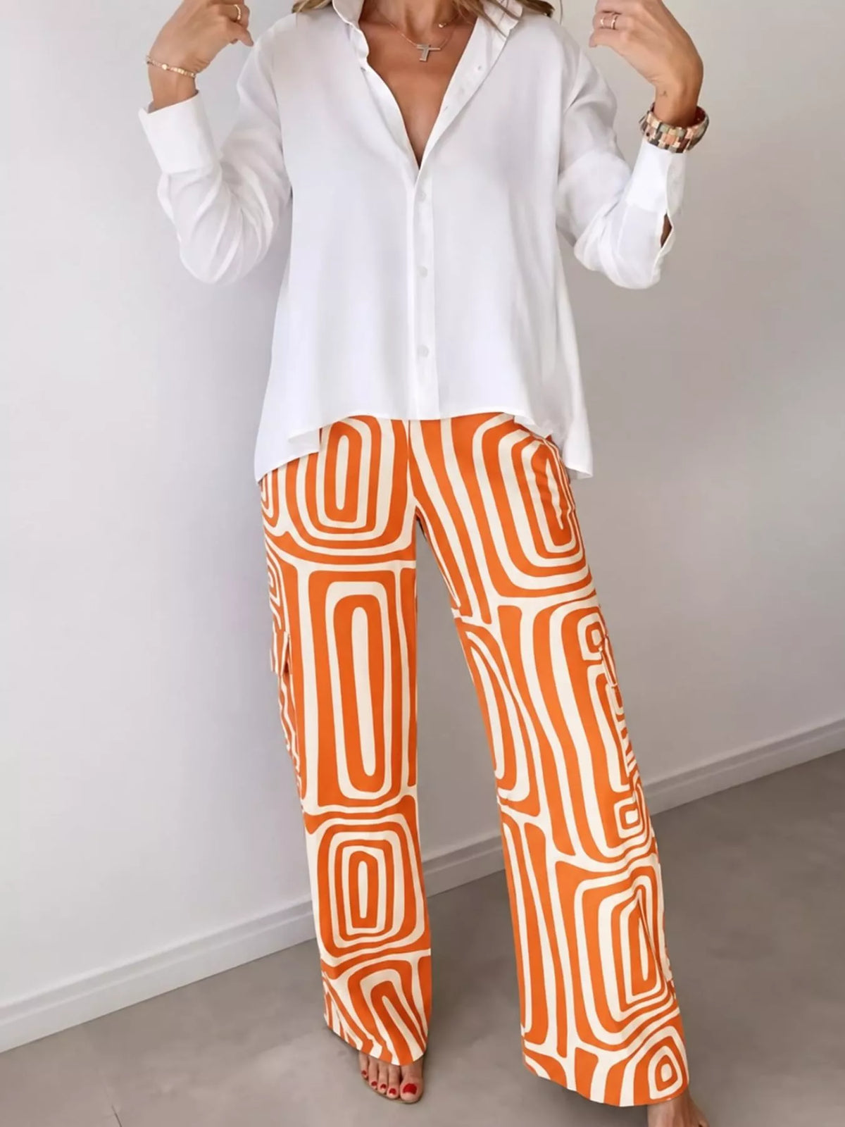 Button-down shirt and geometric patterned pants set in white with orange print.