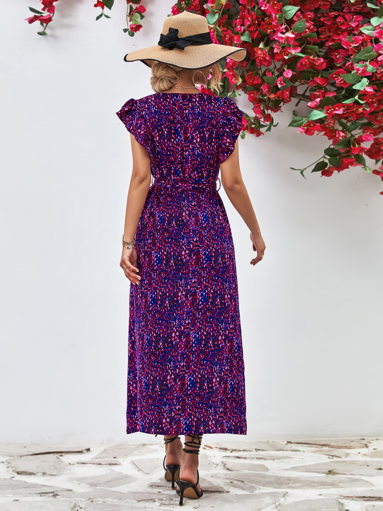 Purple printed surplice neck flutter sleeve slit dress shown from back, midi length with side slit.