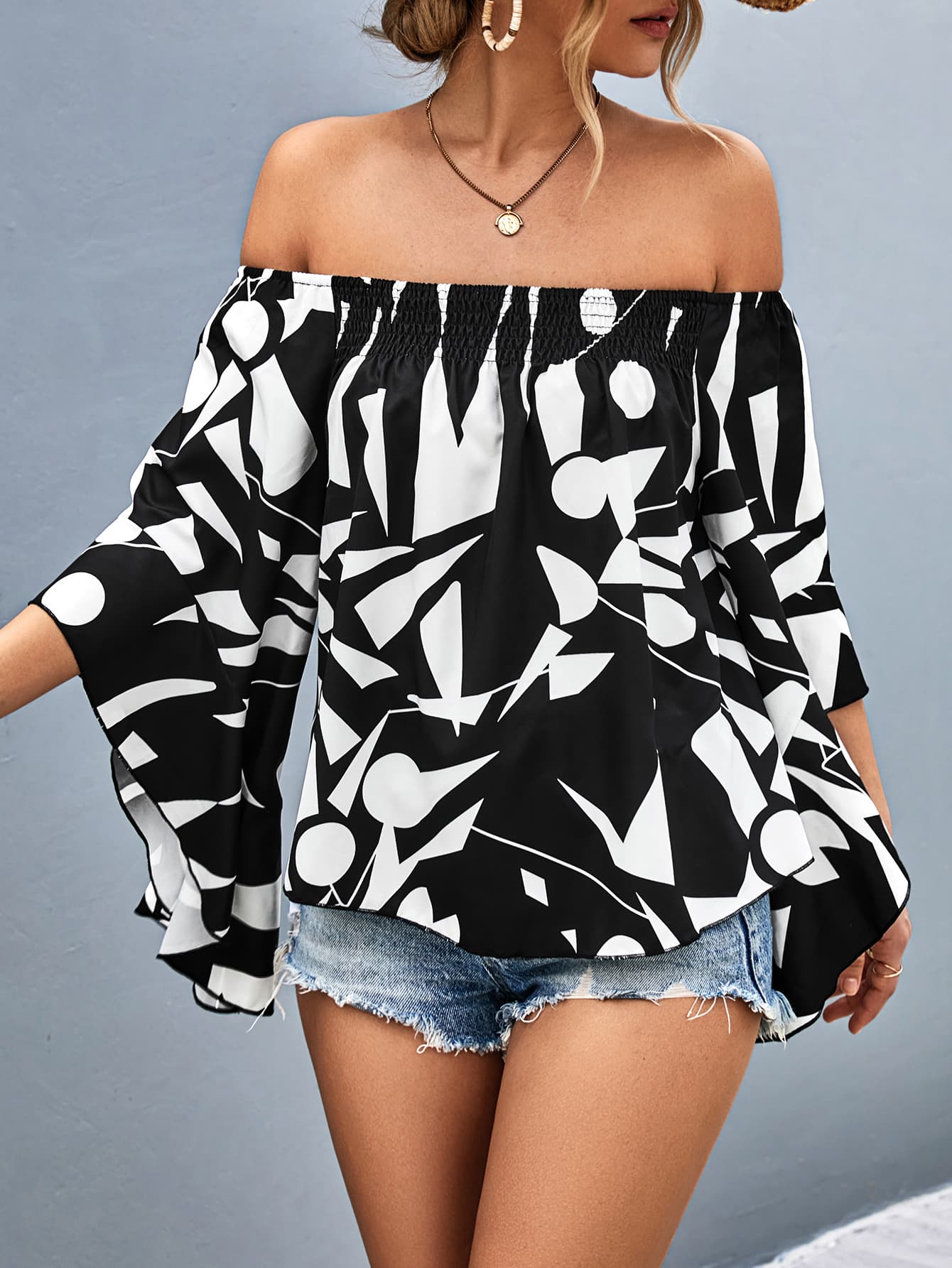 Off-shoulder bell sleeve blouse in black with large white abstract pattern