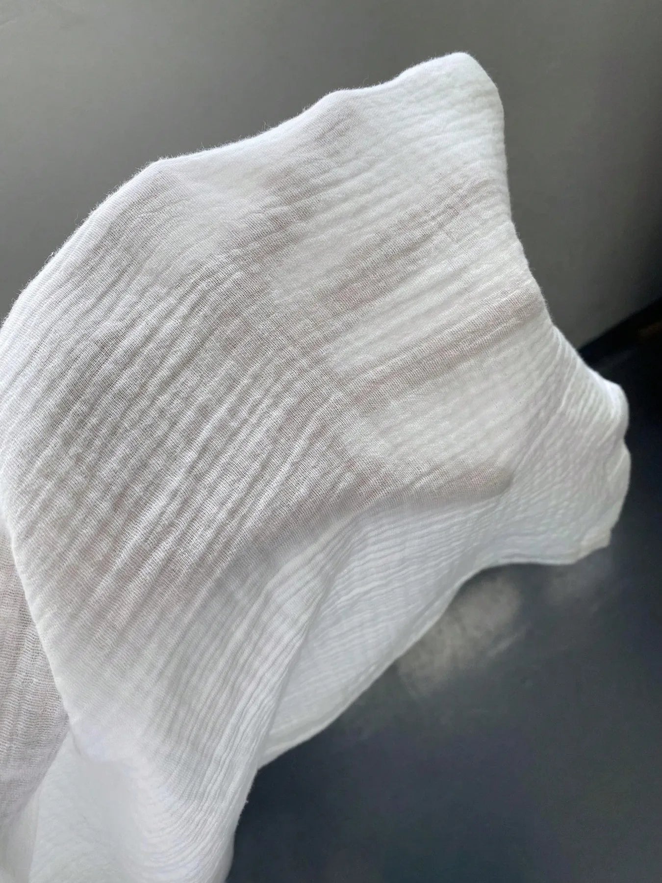 White textured fabric on wide-leg pants, close-up detail.