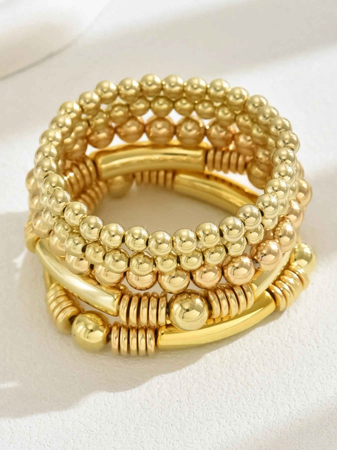 Gold 5-piece beaded bracelet set with stacked bangles and central charm