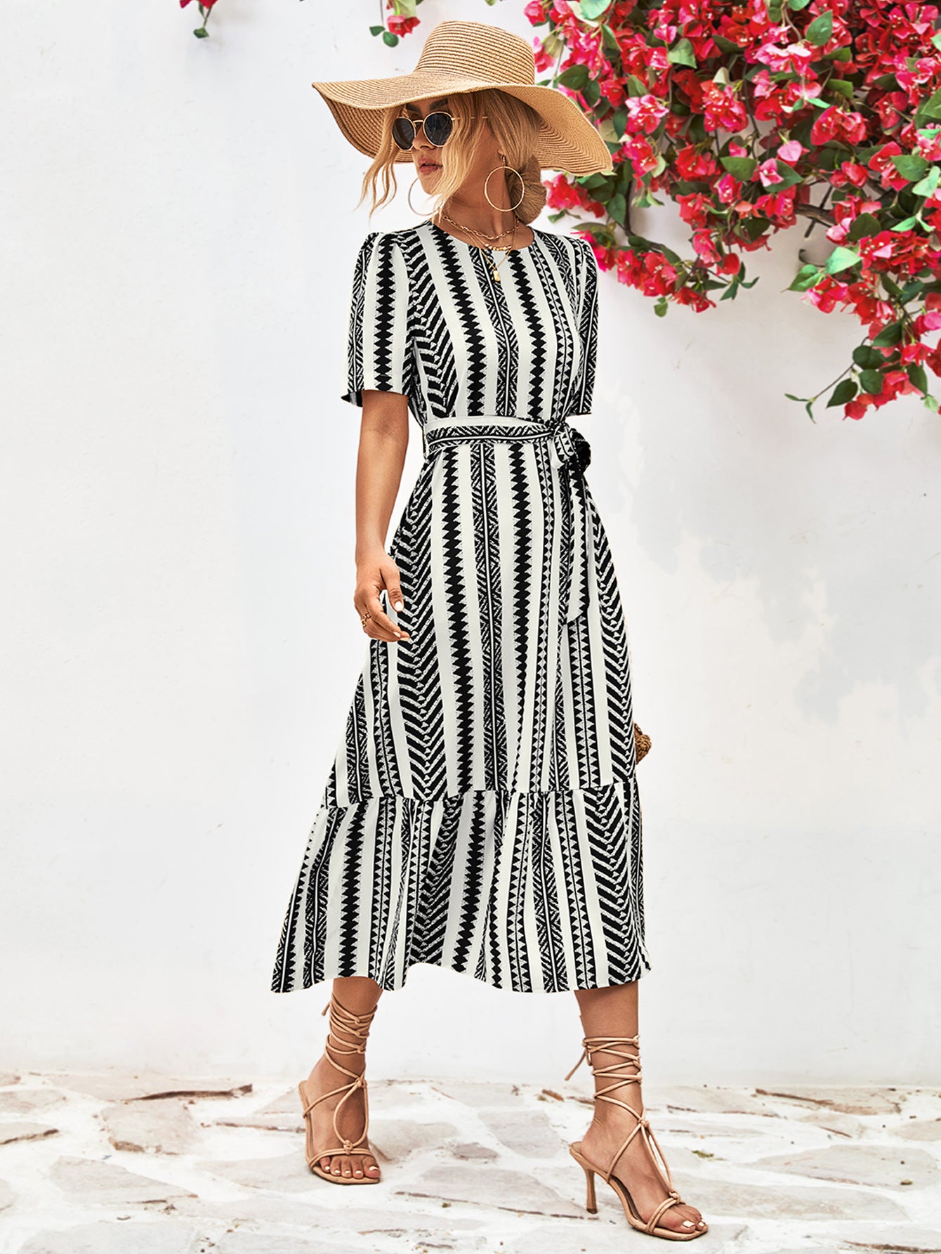 Black striped round-neck puff sleeve dress with tied waist belt, front view wearing hat.