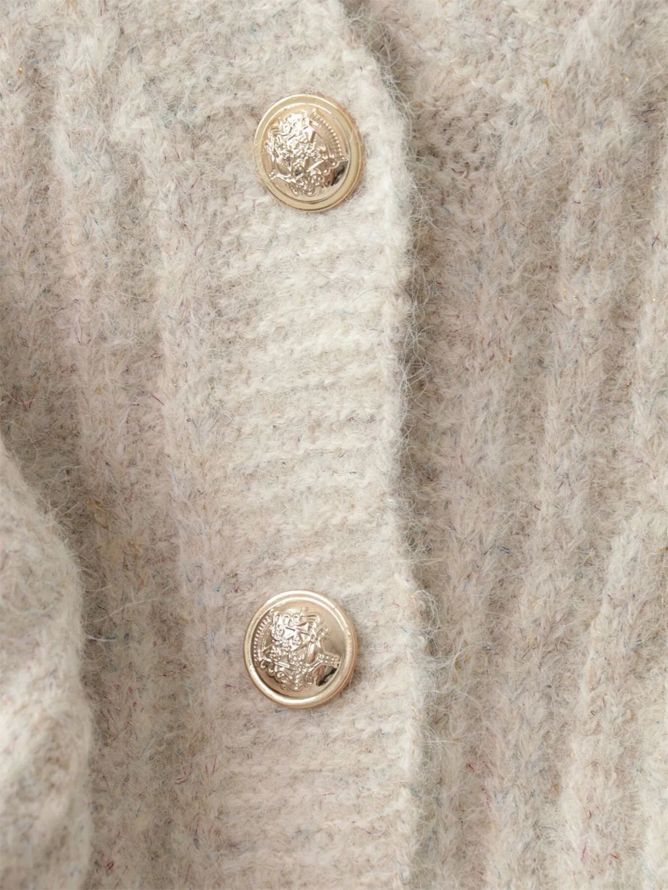 Cream cable-knit cardigan showing two round button details on front placket