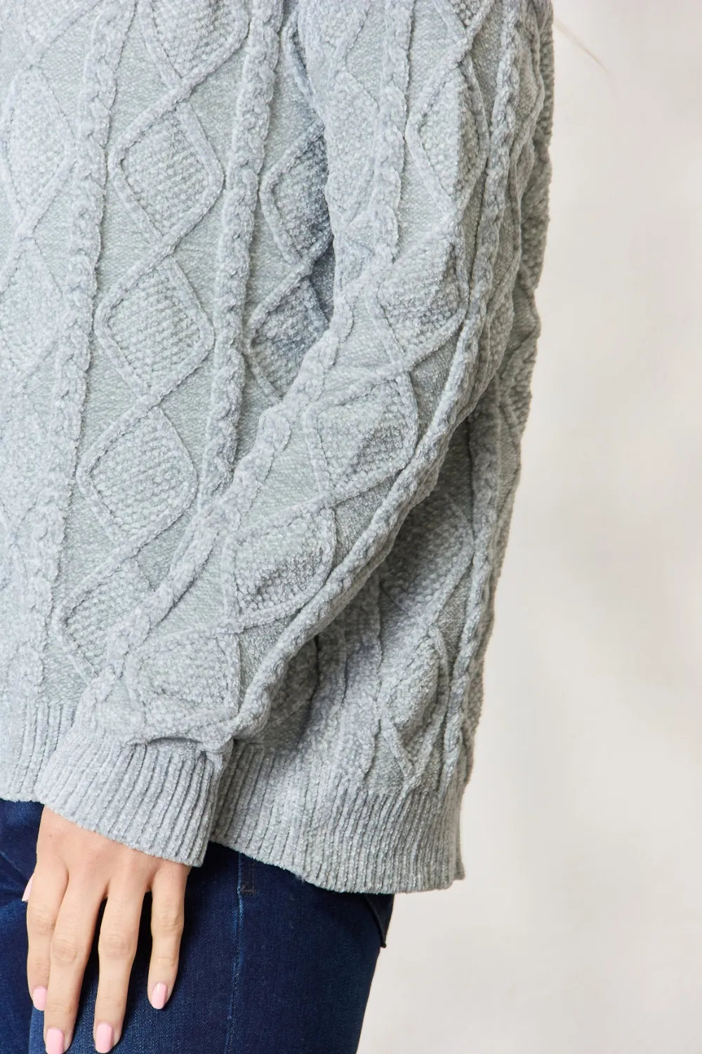 Dust sage cable knit sweater sleeve detail with ribbed cuff and textured cables