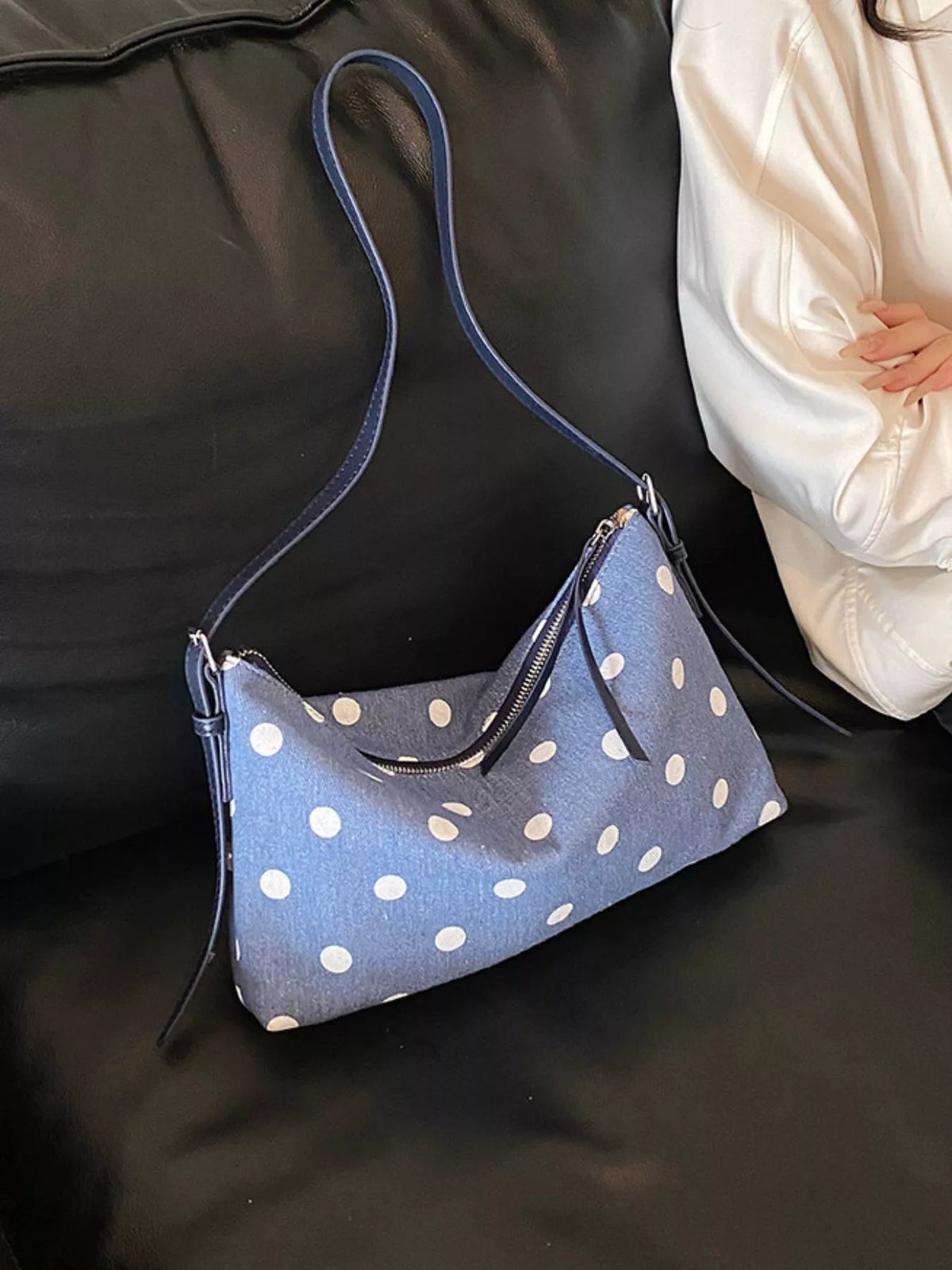 Blue polka dot small shoulder bag on couch with zipper top and metal details