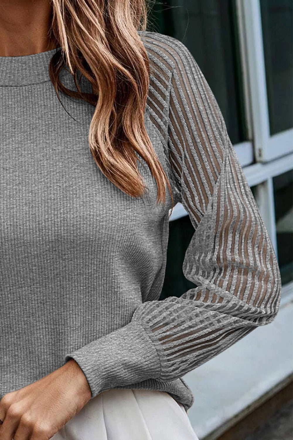 Charcoal knit top close-up: ribbed round neck and striped raglan sleeves