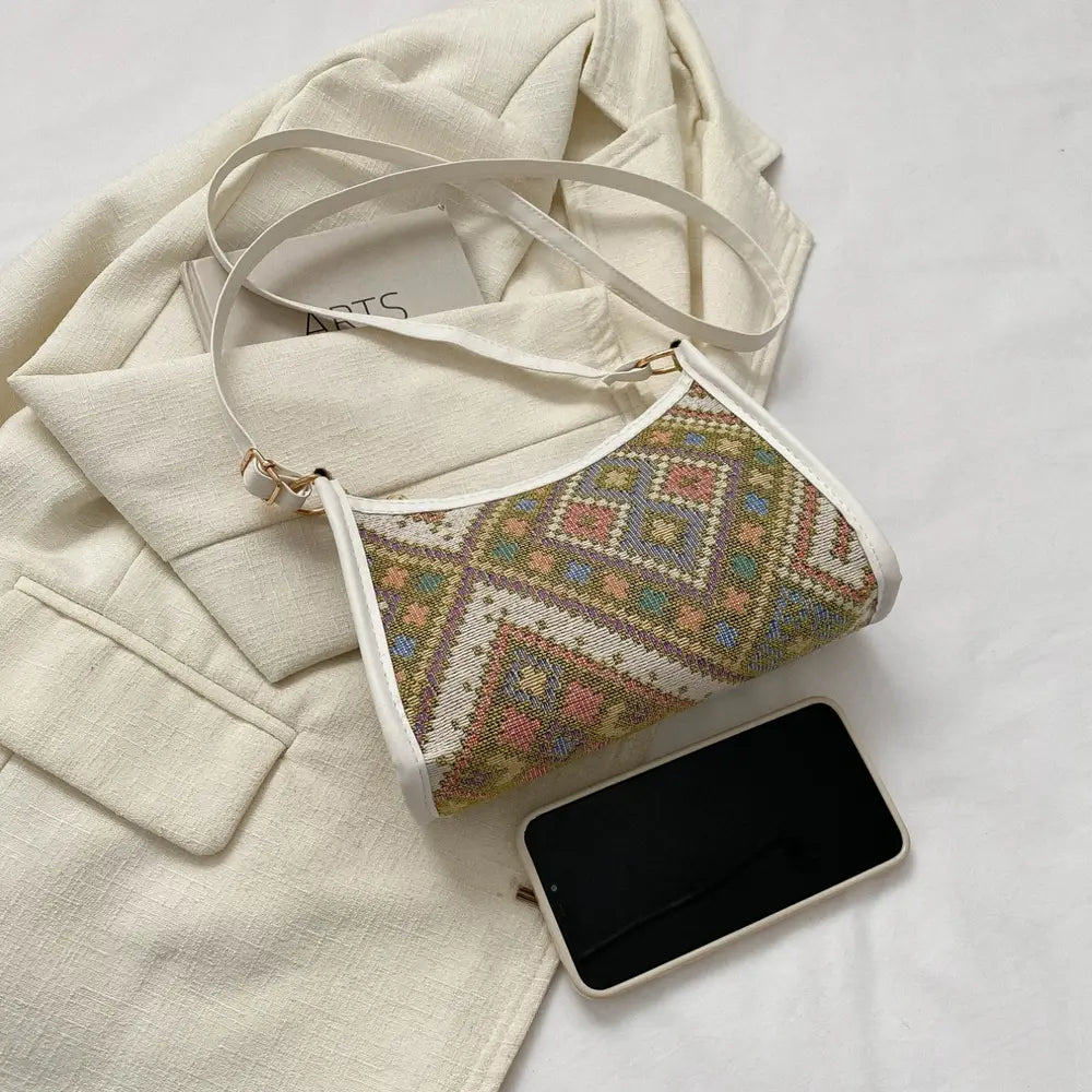 Light crossbody bag with multicolor pattern and adjustable strap, phone beside it